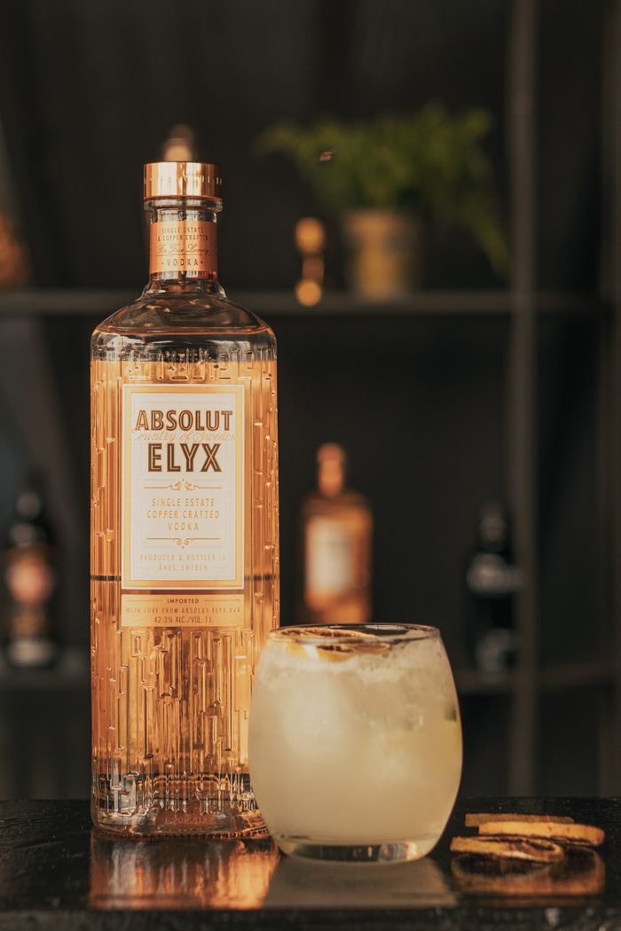 about-01 Stylish Absolut Elyx vodka bottle next to a refreshing cocktail glass on a bar counter.
