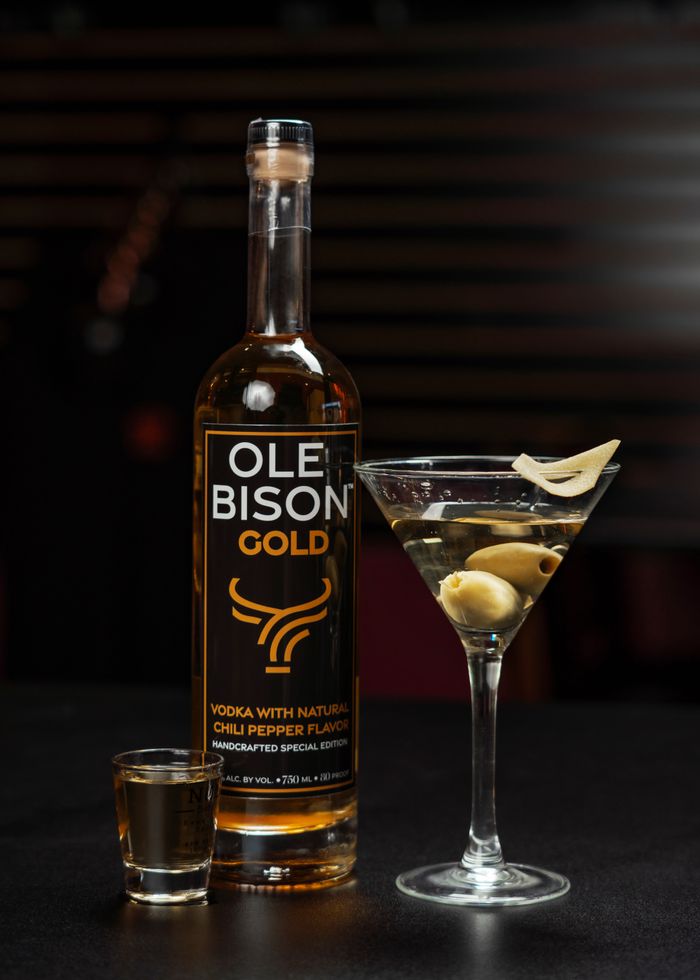services-01 Ole Bison Gold vodka bottle with chili pepper flavor alongside martini with olives. Perfect for spirits enthusiasts.