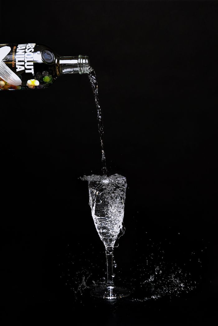 gallery-6 Capture of vodka pouring into a glass creating energetic splashes on a black background.